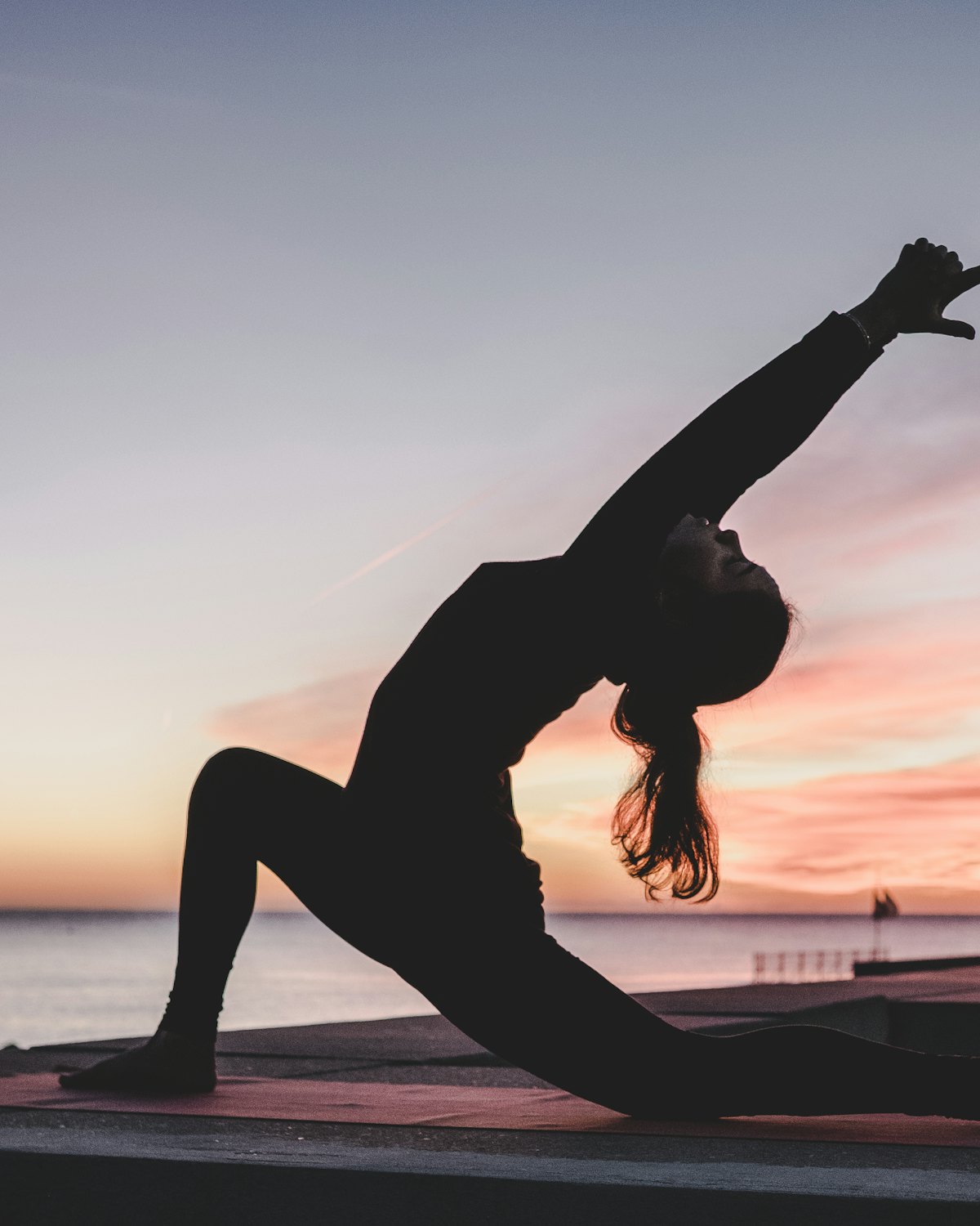 A practitioner moving through a standing pose at golden hour